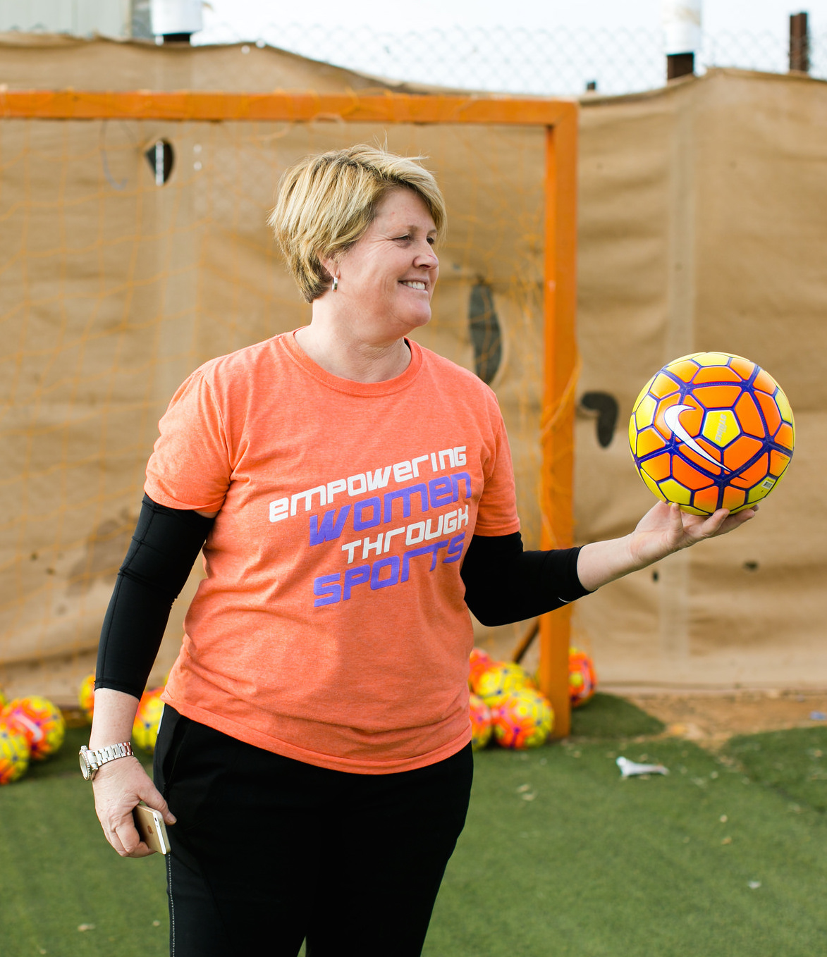 Mary Harvey stands in front of a soccer goal with a colorful Nike soccer ball in her hand. 